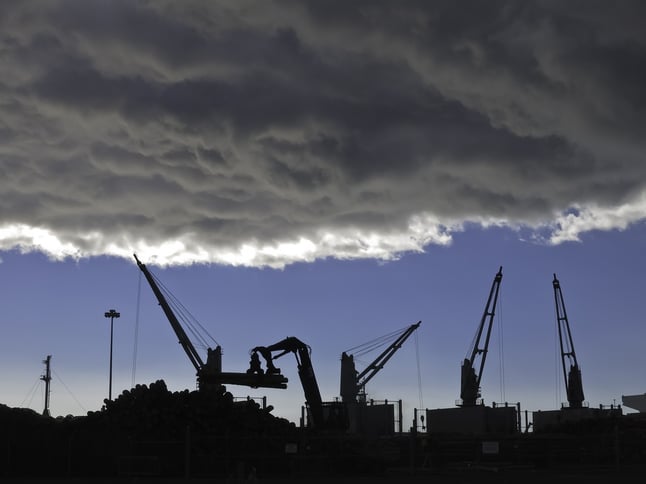 Storm cloud over silhouettes of cranes lifting logs to be shipped from seaport of Astoria, Oregon.jpeg